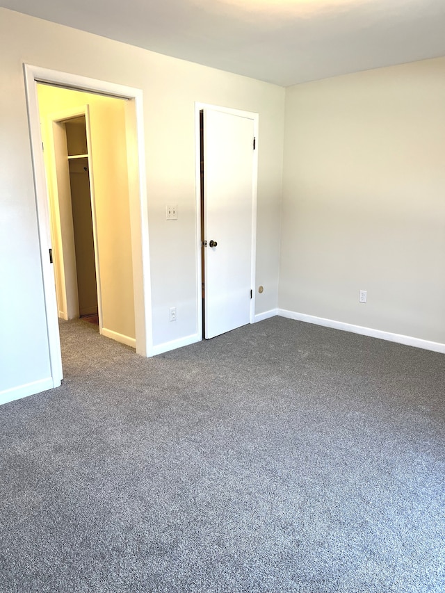 unfurnished bedroom with dark colored carpet and a closet