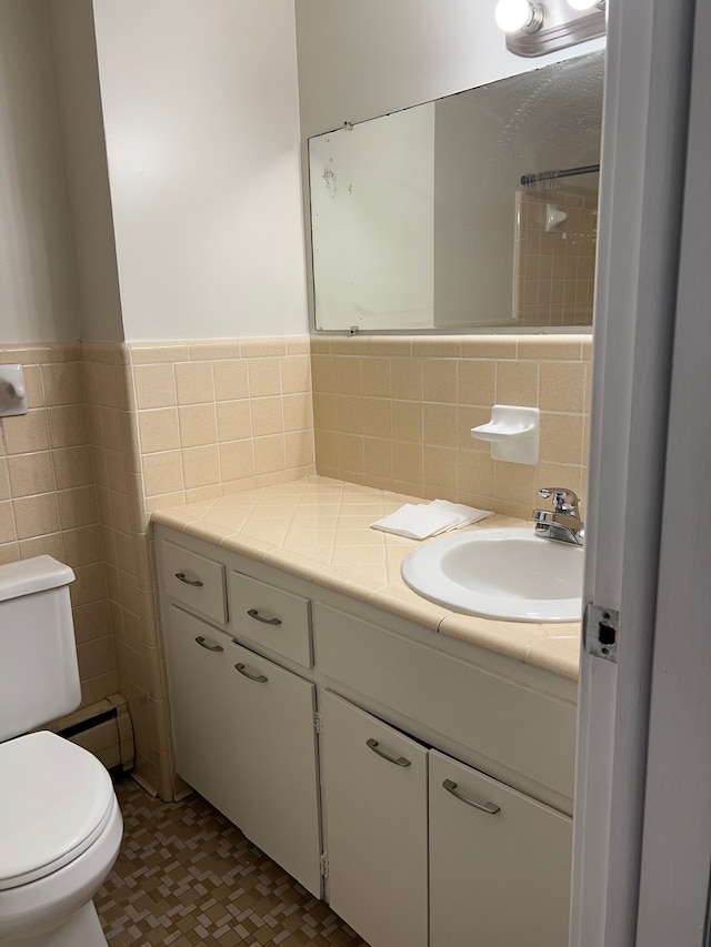 bathroom with vanity, toilet, tile walls, and a baseboard heating unit