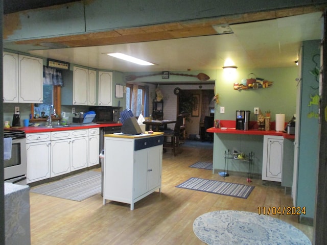 kitchen featuring stainless steel electric stove, light hardwood / wood-style floors, white cabinets, and sink