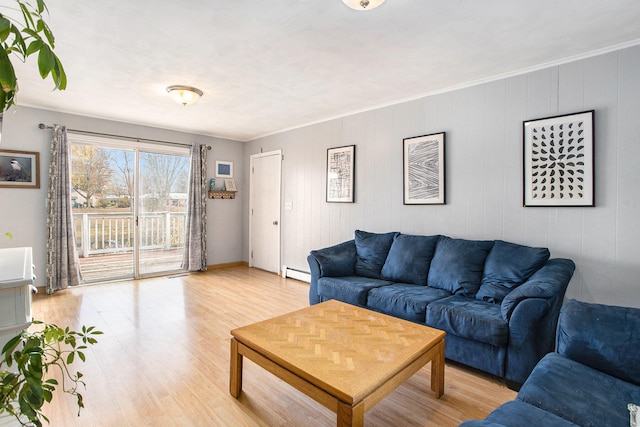 living room with ornamental molding, a baseboard heating unit, and light wood-type flooring