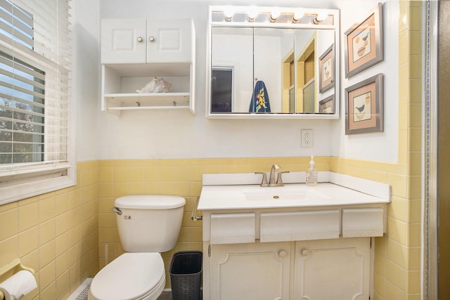 bathroom with vanity, toilet, and tile walls