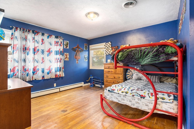 bedroom featuring wood-type flooring, a textured ceiling, and a baseboard radiator