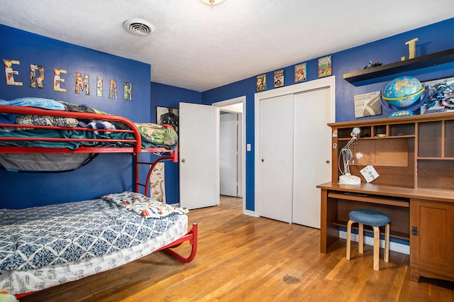 bedroom with hardwood / wood-style floors, a textured ceiling, and a closet