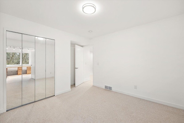 unfurnished bedroom featuring light carpet and a closet