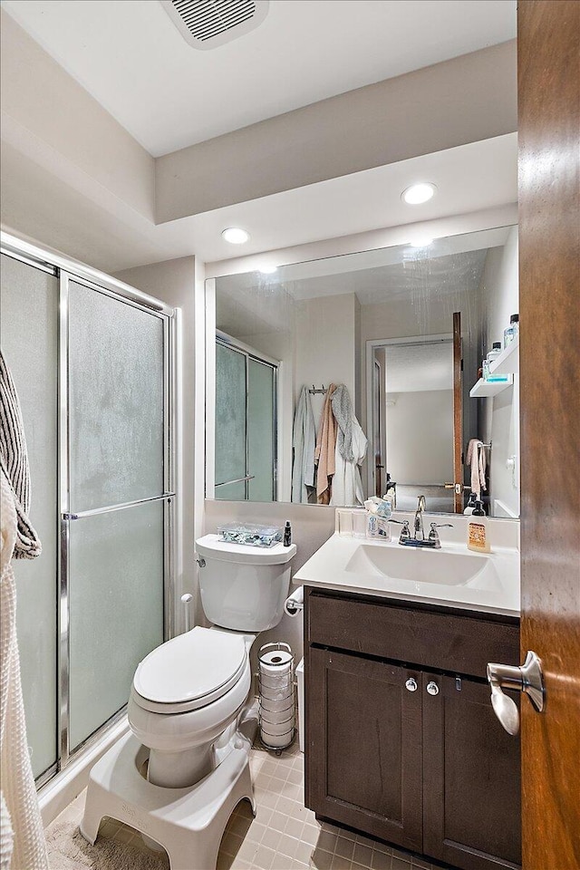 bathroom with vanity, toilet, and a shower with shower door