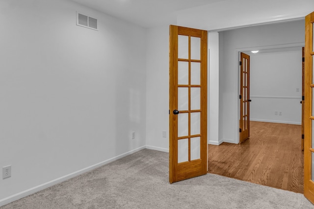 carpeted spare room featuring french doors