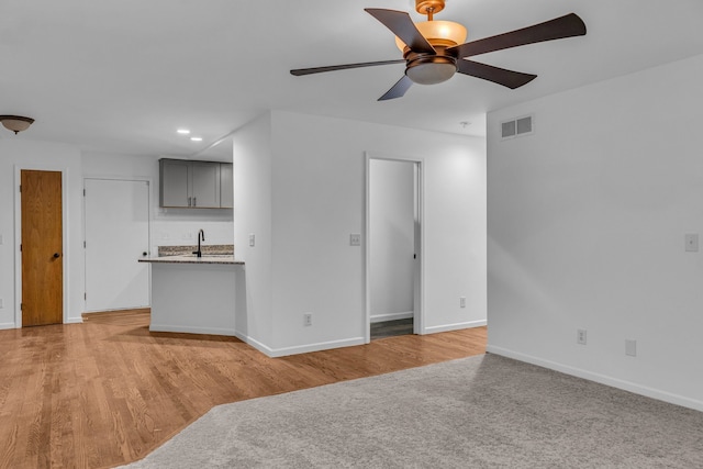 unfurnished living room featuring ceiling fan, sink, and light hardwood / wood-style flooring