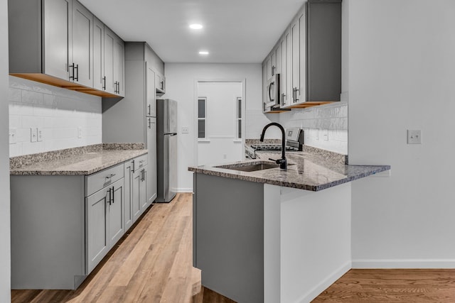 kitchen with gray cabinetry, light hardwood / wood-style floors, sink, and appliances with stainless steel finishes