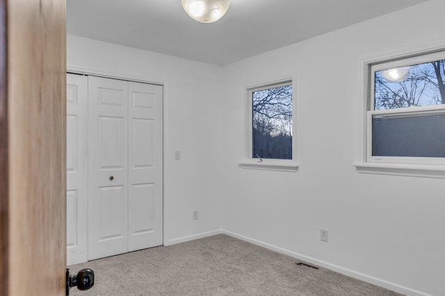 unfurnished bedroom with light carpet and a closet