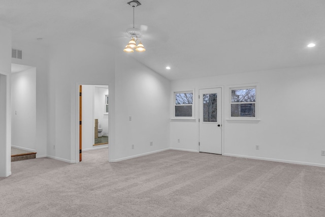 spare room featuring light colored carpet and lofted ceiling