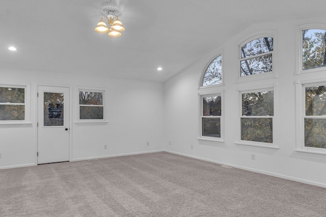 unfurnished living room with light carpet, a chandelier, and high vaulted ceiling