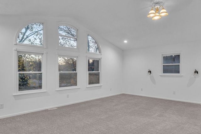 carpeted empty room with high vaulted ceiling and a notable chandelier