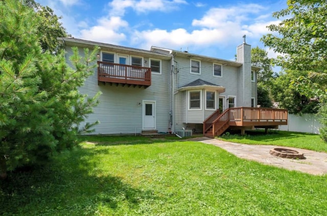 rear view of property featuring central AC unit, a balcony, a yard, and an outdoor fire pit