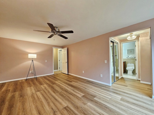 unfurnished bedroom with ceiling fan with notable chandelier, ensuite bath, and light hardwood / wood-style flooring