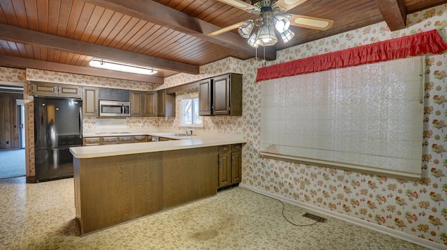 kitchen featuring black refrigerator, kitchen peninsula, dark brown cabinets, wooden ceiling, and beamed ceiling