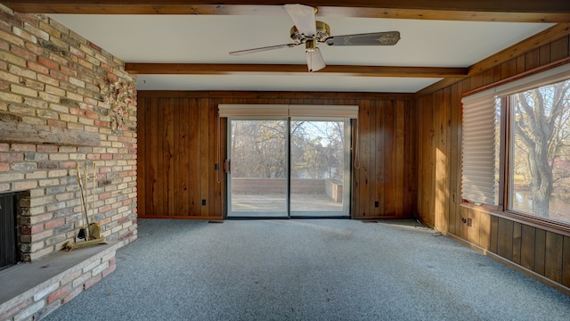 unfurnished living room with beam ceiling, light colored carpet, ceiling fan, and wooden walls