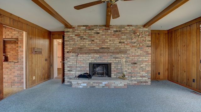 unfurnished living room featuring beamed ceiling, carpet, and wooden walls