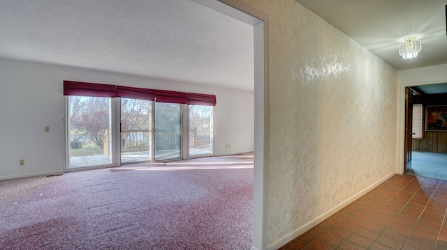 carpeted spare room with a textured ceiling and an inviting chandelier