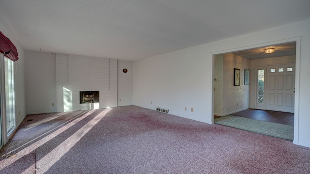 unfurnished living room featuring carpet and a brick fireplace