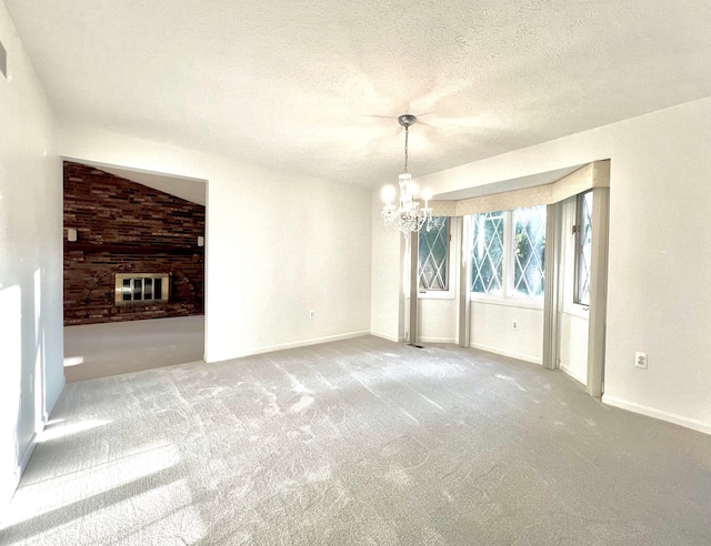 interior space with carpet, a brick fireplace, a textured ceiling, and an inviting chandelier