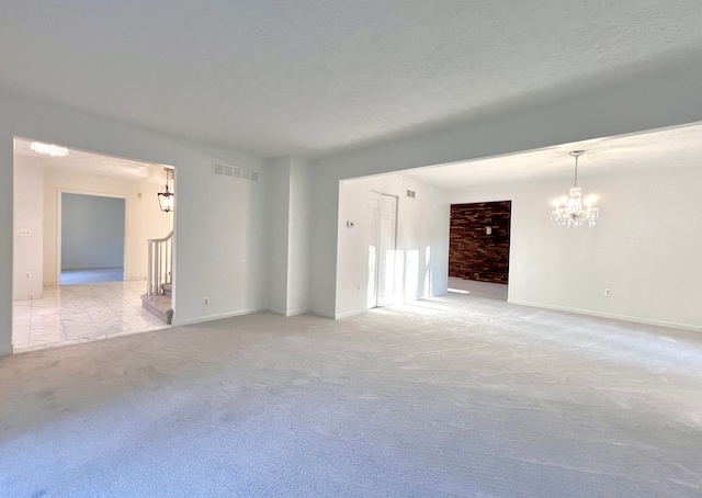 carpeted spare room with a chandelier and a textured ceiling