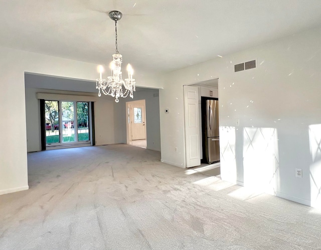 empty room with light carpet and a notable chandelier