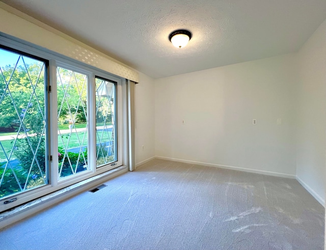 carpeted spare room with a textured ceiling