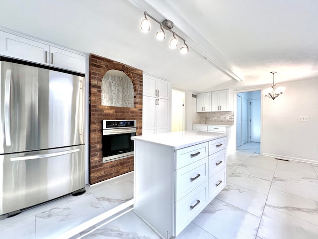 kitchen with stainless steel appliances, decorative light fixtures, a chandelier, a center island, and white cabinetry