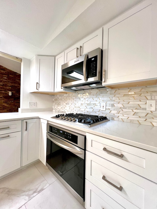 kitchen featuring appliances with stainless steel finishes, tasteful backsplash, a textured ceiling, light tile patterned floors, and white cabinetry