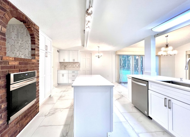 kitchen featuring a center island, hanging light fixtures, appliances with stainless steel finishes, a notable chandelier, and white cabinetry