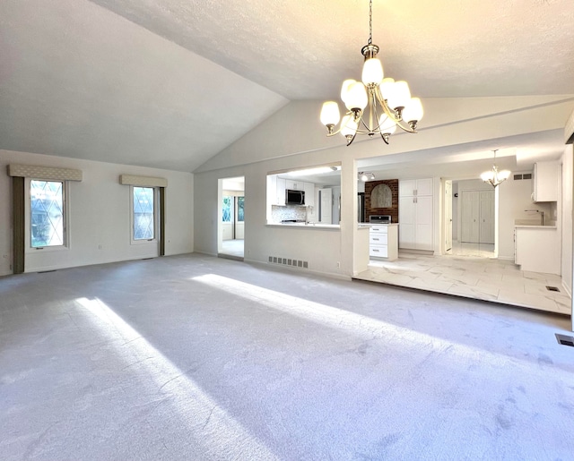 unfurnished living room featuring light carpet, a healthy amount of sunlight, vaulted ceiling, and an inviting chandelier