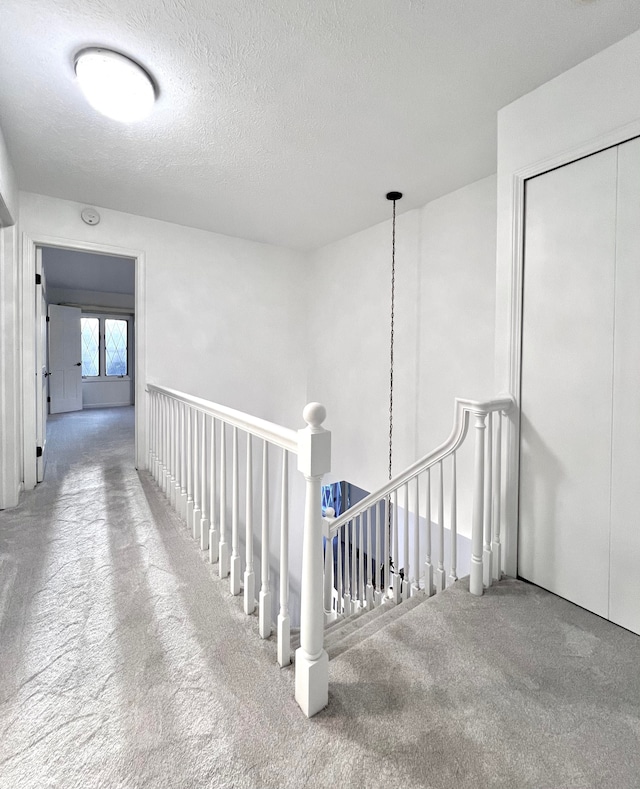 hallway with carpet flooring and a textured ceiling