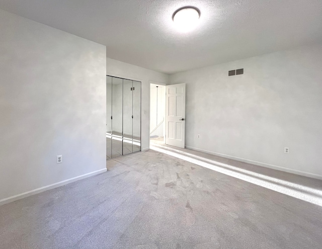 unfurnished bedroom with a textured ceiling, light carpet, and a closet