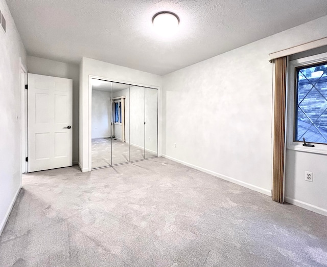 unfurnished bedroom featuring a closet, light colored carpet, and a textured ceiling