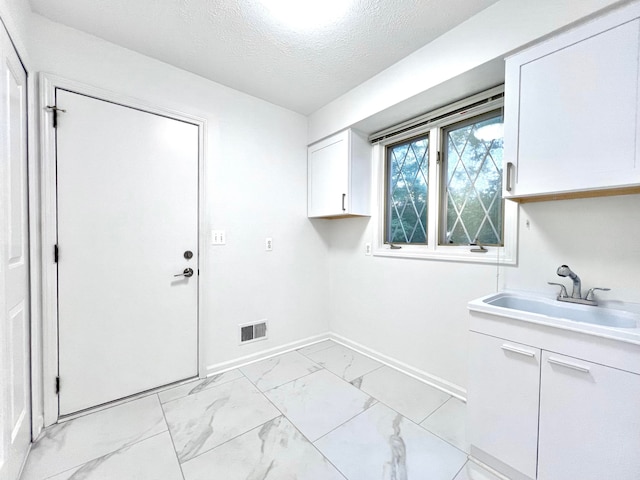 laundry room with sink and a textured ceiling