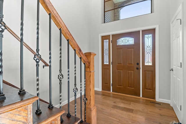 foyer entrance with light hardwood / wood-style floors and a towering ceiling