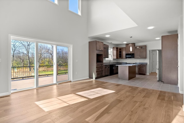 unfurnished living room featuring a high ceiling and light hardwood / wood-style floors