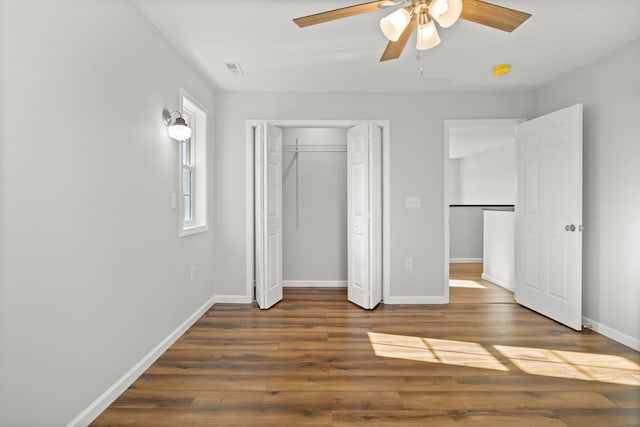 unfurnished bedroom with a closet, ceiling fan, and dark wood-type flooring