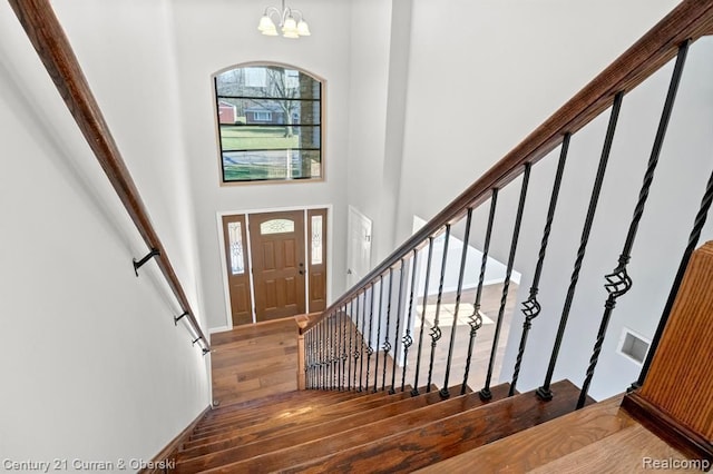 entryway with dark hardwood / wood-style floors, a high ceiling, and a chandelier