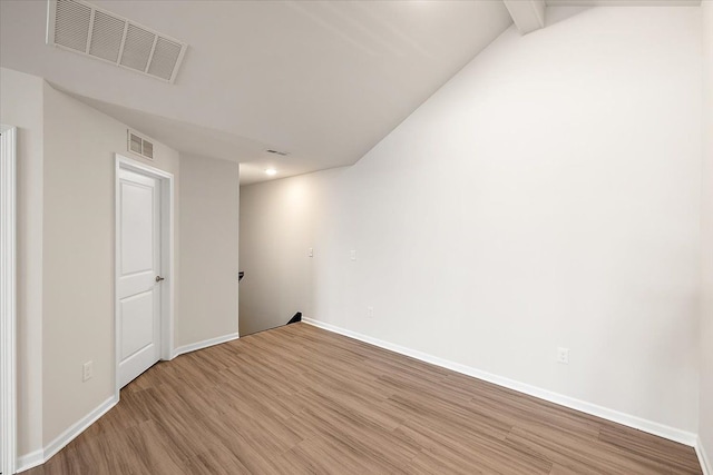 unfurnished room featuring lofted ceiling with beams and light hardwood / wood-style floors