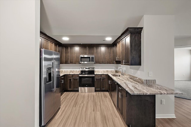 kitchen featuring kitchen peninsula, sink, light hardwood / wood-style flooring, and appliances with stainless steel finishes