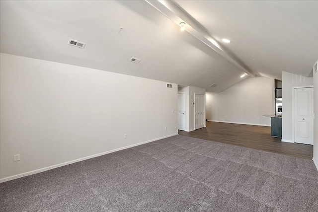 interior space with dark colored carpet and lofted ceiling with beams