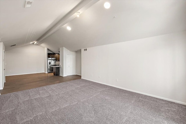 unfurnished living room with vaulted ceiling with beams and carpet floors