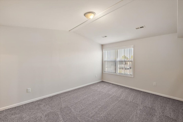 carpeted spare room with vaulted ceiling