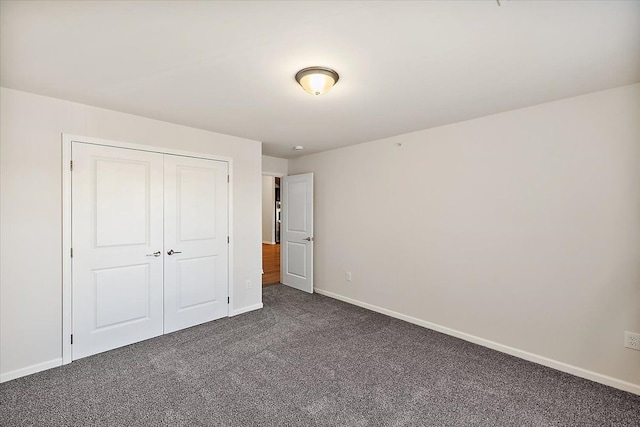 unfurnished bedroom featuring dark colored carpet and a closet