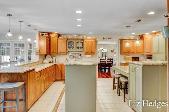 kitchen with a kitchen breakfast bar, light tile patterned floors, decorative light fixtures, a kitchen island, and kitchen peninsula