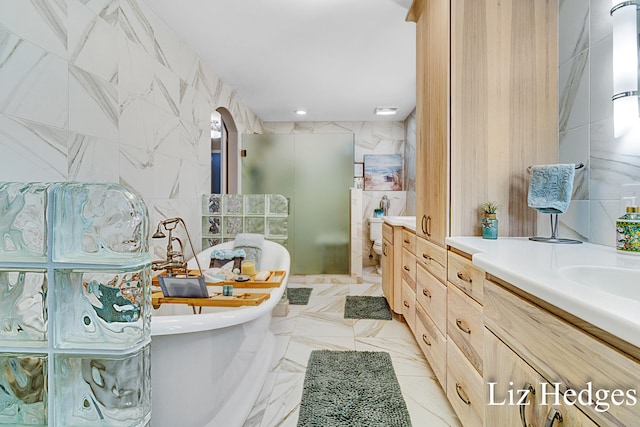 bathroom with vanity, tile walls, and a tub