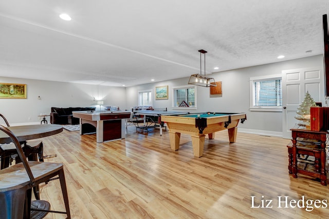 game room featuring a textured ceiling, pool table, and light hardwood / wood-style flooring