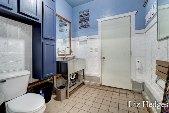 bathroom with tile patterned flooring, toilet, and tile walls