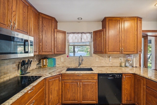 kitchen with sink, backsplash, light stone counters, and black appliances